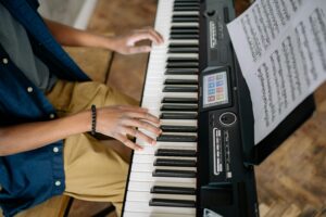 Mulher tocando teclado digital em ambiente noturno e acolhedor, ilustrando os benefícios de aprender teclado para memória, concentração e relaxamento