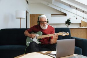 Pessoa tocando guitarra em casa à noite, usando a música como refúgio para aliviar o estresse e encontrar bem-estar emocional