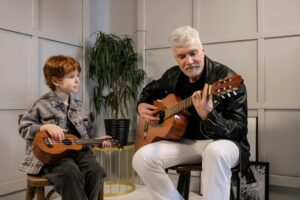 Pessoa tocando violão em casa à noite, usando a música como refúgio para aliviar o estresse e encontrar bem-estar emocional